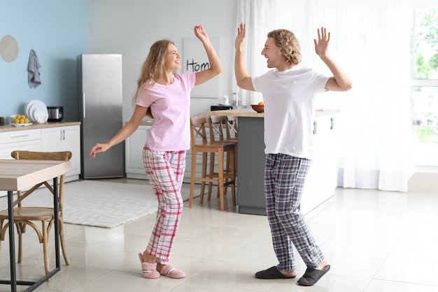 Feliz pareja joven bailando en la cocina