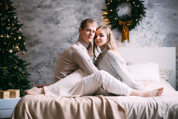 Feliz pareja joven en la cama en casa