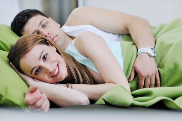 feliz pareja joven en la cama por la mañana