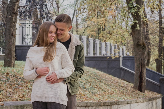 Feliz pareja joven caminando en un día de otoño en el parque.