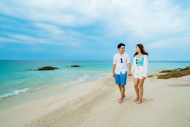 Feliz pareja joven caminando por la playa en la isla de Koh MunNork, Rayong, Tailandia