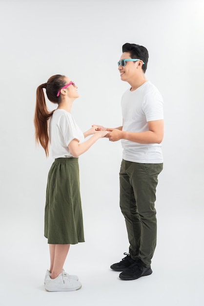 Feliz pareja joven en camisetas blancas bailando y sonriendo a la cámara aislada en blanco