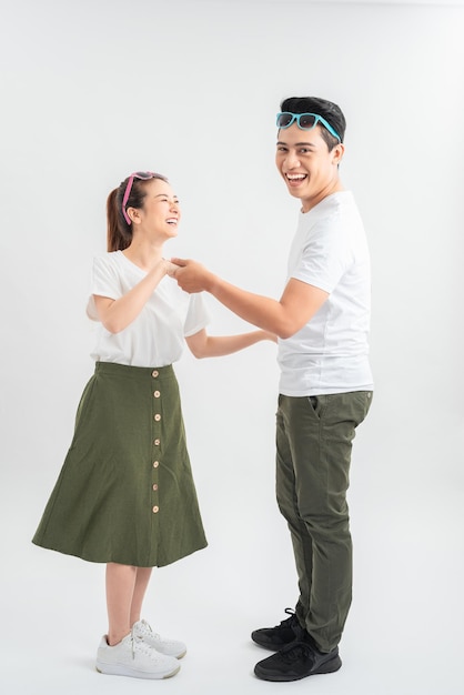 Feliz pareja joven en camisetas blancas bailando y sonriendo a la cámara aislada en blanco