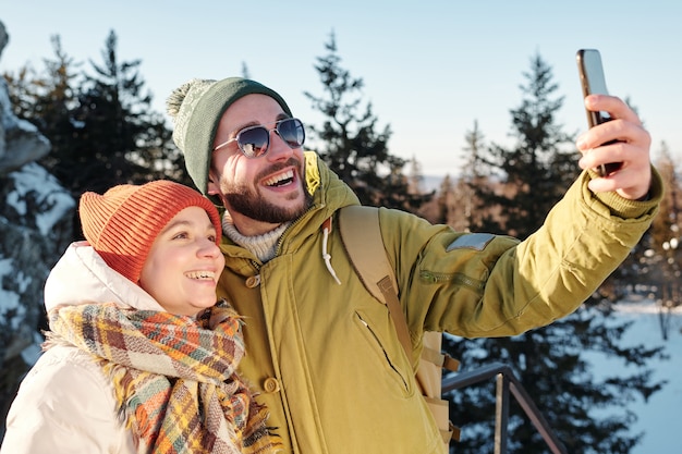 Feliz pareja joven caucásica haciendo selfie en el bosque