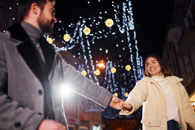 Feliz pareja joven celebrando el Año Nuevo al aire libre en la calle