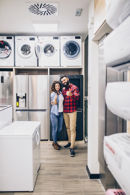 Feliz pareja joven comprando electrodomésticos en la tienda.