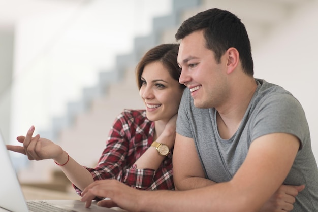 feliz pareja joven comprando en línea usando una computadora portátil y una tarjeta de crédito en su villa de lujo