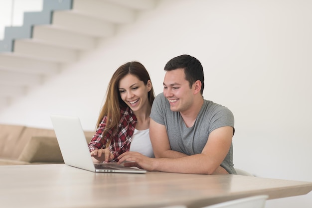 feliz pareja joven comprando en línea usando una computadora portátil y una tarjeta de crédito en su villa de lujo