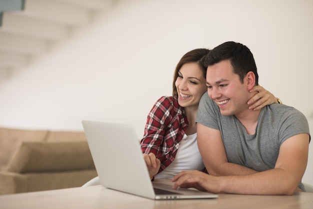 feliz pareja joven comprando en línea usando una computadora portátil y una tarjeta de crédito en su villa de lujo