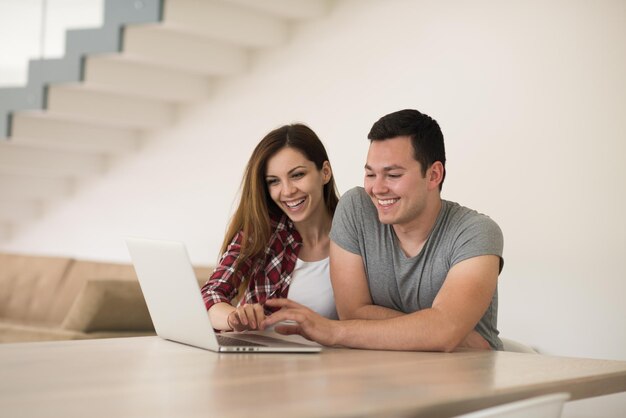 feliz pareja joven comprando en línea usando una computadora portátil y una tarjeta de crédito en su villa de lujo