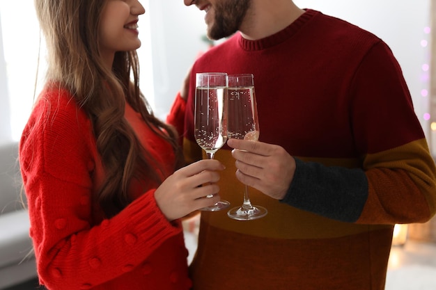 Feliz pareja joven con copas de champán celebrando la Navidad en casa