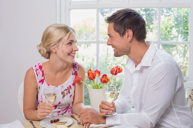 Feliz pareja joven con copas de vino con comida