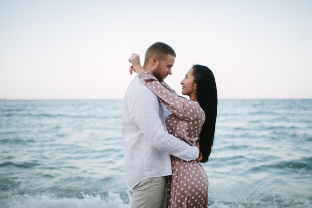 Feliz pareja joven corriendo en la playa cerca del mar Viaje de luna de miel