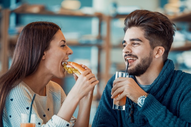 Feliz pareja joven desayunando en la cafetería