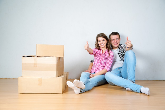 Feliz pareja joven desempacando o empacando cajas y mudándose a un nuevo hogar.