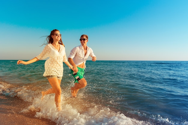 Feliz pareja joven disfrutando del mar