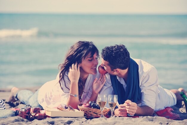 feliz pareja joven disfrutando de un picnic en la playa y pasando un buen rato en las vacaciones de verano