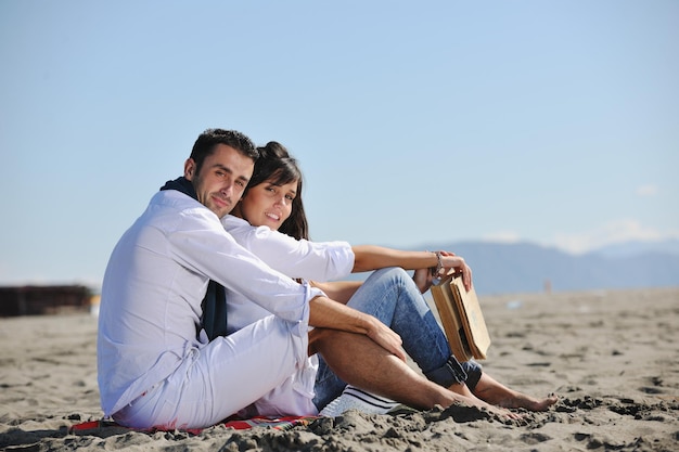 feliz pareja joven disfrutando de un picnic en la playa y pasando un buen rato en las vacaciones de verano