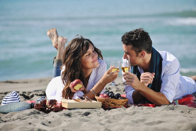 feliz pareja joven disfrutando de un picnic en la playa y pasando un buen rato en las vacaciones de verano