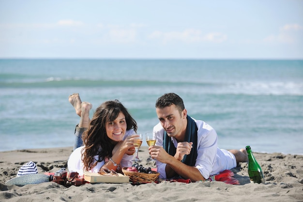 feliz pareja joven disfrutando de un picnic en la playa y pasando un buen rato en las vacaciones de verano