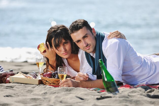 feliz pareja joven disfrutando de un picnic en la playa y pasando un buen rato en las vacaciones de verano