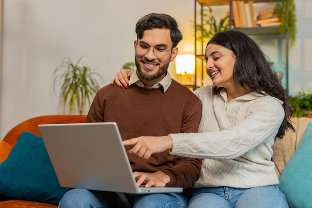 Feliz pareja joven y diversa familia discutiendo la planificación juntos reservando mientras usan la computadora portátil en casa