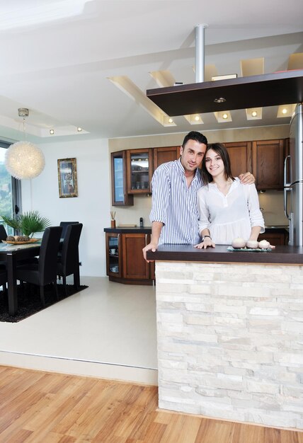 Foto feliz pareja joven se divierte en la moderna cocina de madera interior mientras prepara comida fresca