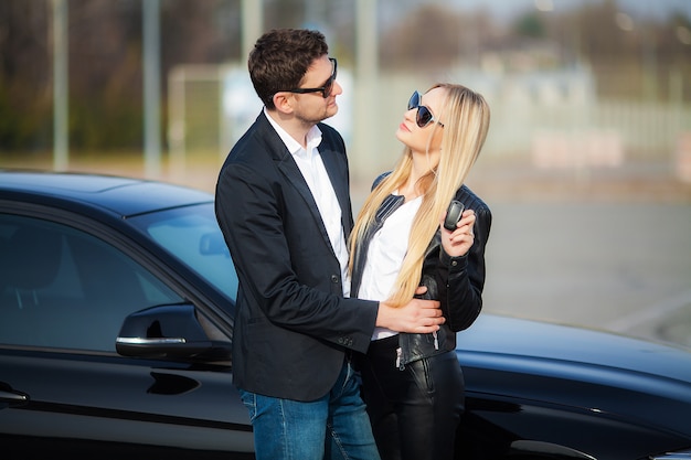 Feliz pareja joven elige y compra un auto nuevo para la familia