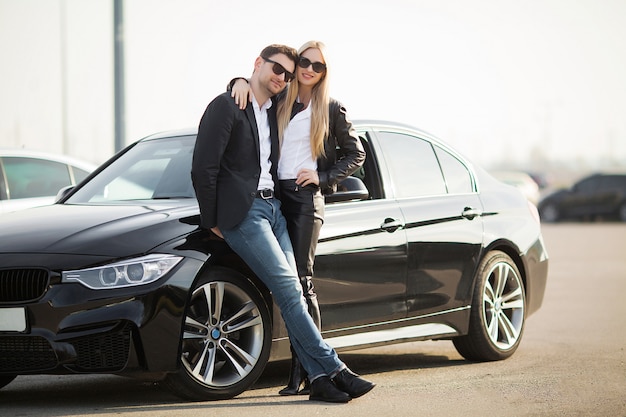 Feliz pareja joven elige y compra un auto nuevo para la familia