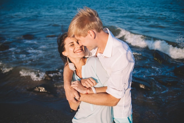 Feliz pareja joven enamorada contra el mar caminar en la playa contra el cielo azul y divertirse en el día de verano Unión amor familia