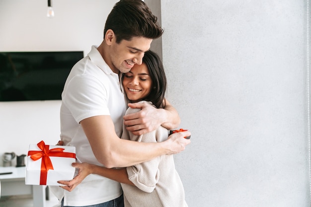 Feliz pareja joven encantadora celebrando juntos, de pie en casa