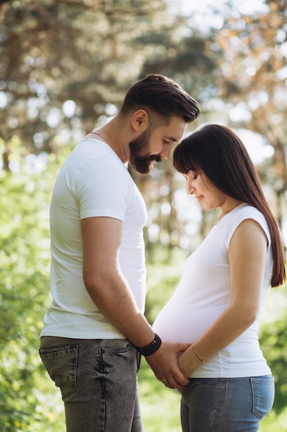 Foto feliz pareja joven esperando bebé en el parque de verano