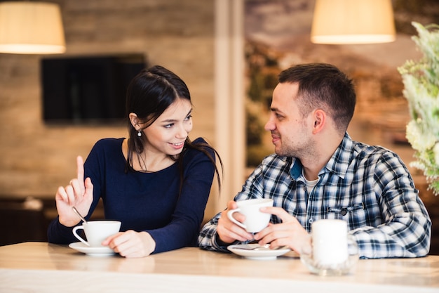 Feliz pareja joven hablando en un café