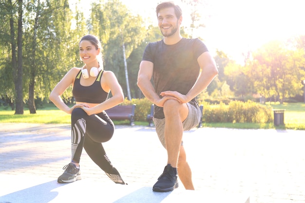 Feliz pareja joven haciendo ejercicio juntos en un parque.