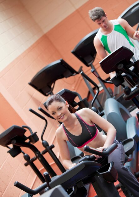 Feliz pareja joven haciendo ejercicios con equipos en un centro deportivo