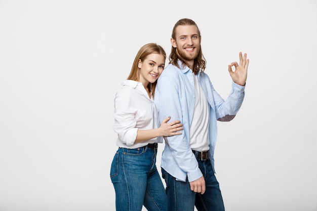 Feliz pareja joven haciendo gesto Ok, aislado sobre fondo blanco