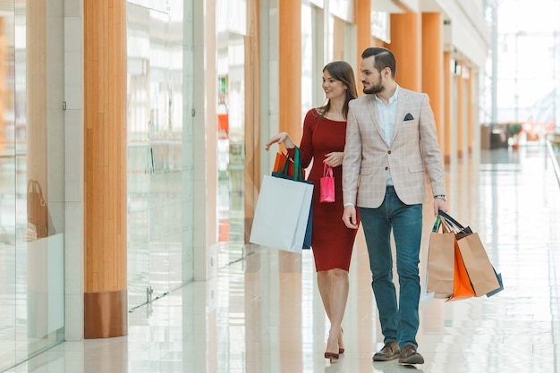 Feliz pareja joven hermosa con bolsas de compras en el centro comercial