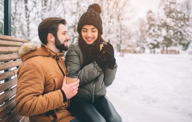 Feliz pareja joven en invierno tomando un café en un paisaje nevado