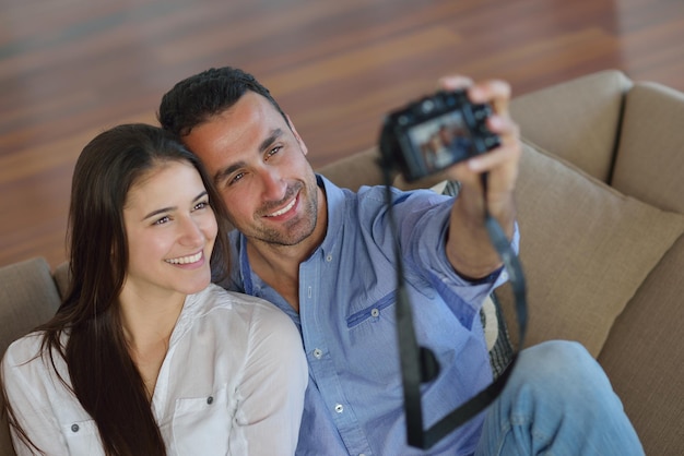 feliz pareja joven jugando con una cámara digital en casa