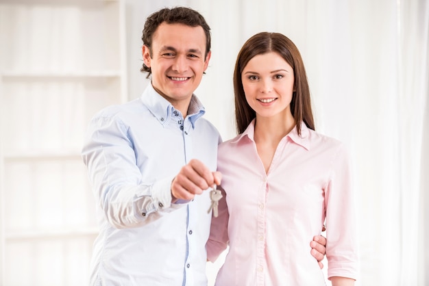 Feliz pareja joven con llaves en su nuevo apartamento.