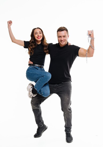 Foto feliz pareja joven con las manos levantadas de pie sobre fondo blanco pareja exitosa celebrando