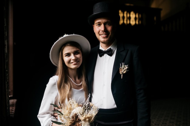 Feliz pareja joven Novias con sombreros Chica joven con un vestido de novia blanco y un sombrero con un ramo de flores Novias en el castillo Novia y novio