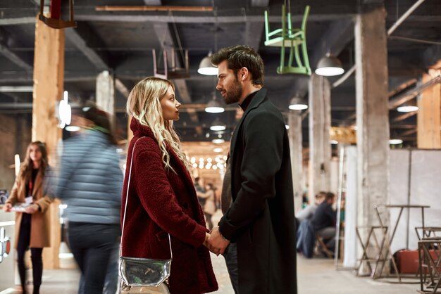 Feliz pareja joven de pie alrededor del pequeño mercado callejero gente borrosa en la foto