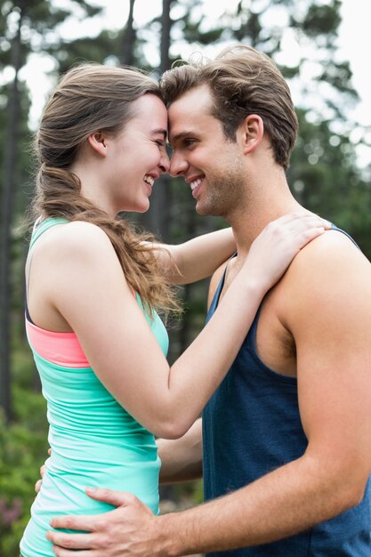 Feliz pareja joven de pie en el bosque