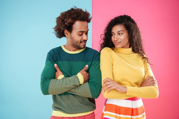 Feliz pareja joven de pie con los brazos cruzados y mirando el uno al otro