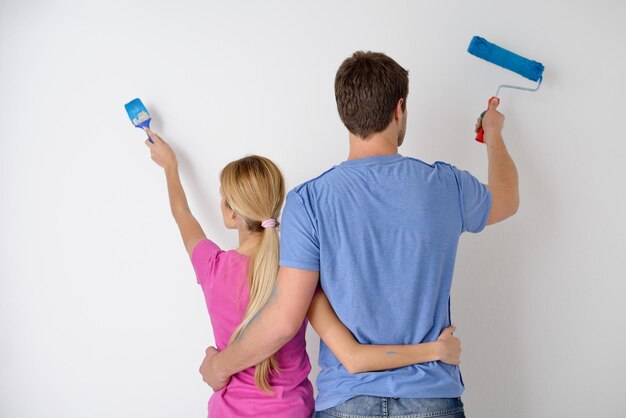 Foto feliz pareja joven pinta en color verde y azul la pared blanca de su nuevo hogar