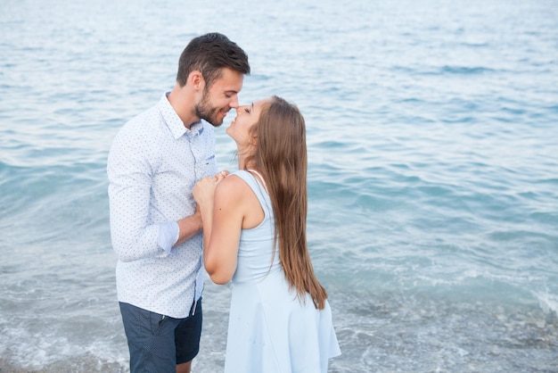 Feliz pareja joven en la playa enamorada abrazándose y abrazándose sonriendo