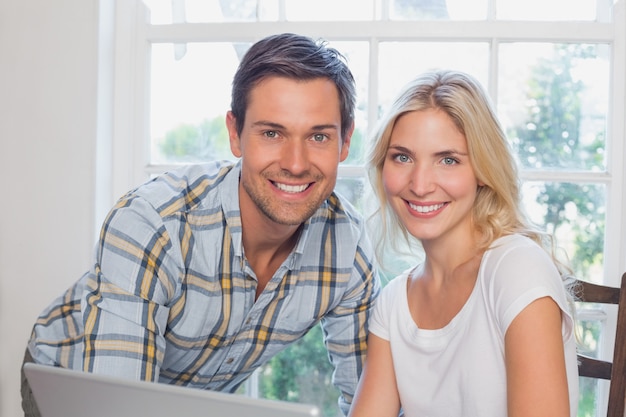 Feliz pareja joven con portátil en casa