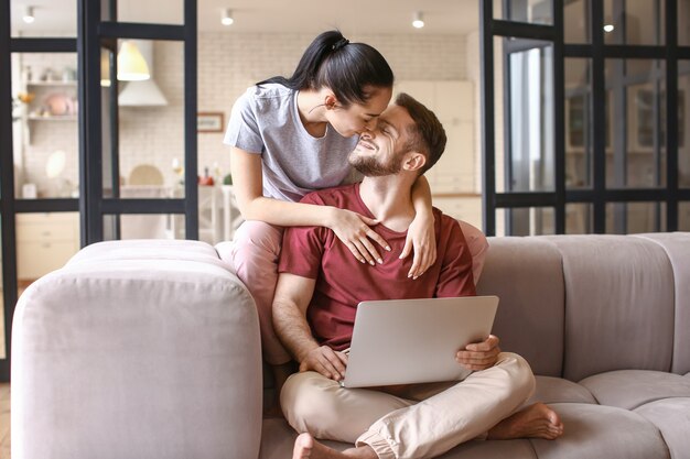 Feliz pareja joven con portátil en casa