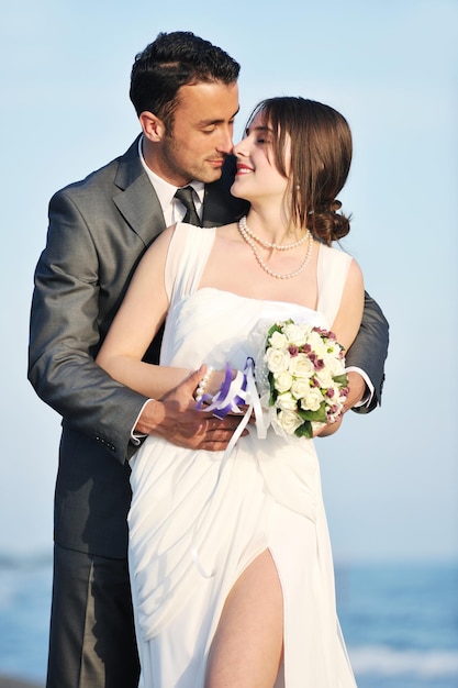 feliz pareja joven recién casada celebrando y divirtiéndose en la hermosa puesta de sol en la playa